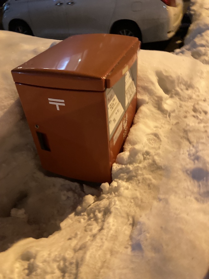 雪に埋もれかけた街角の郵便ポスト
